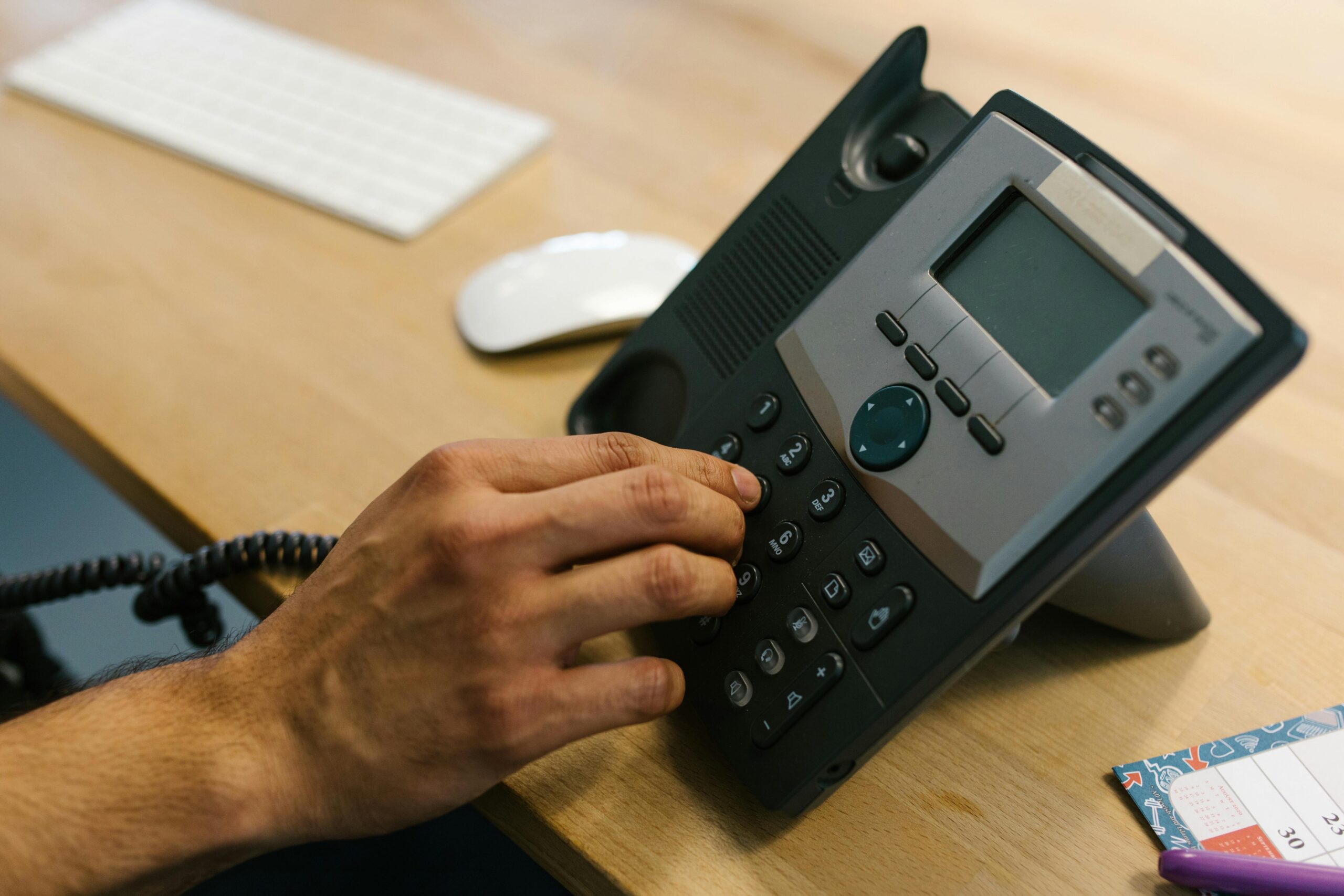 A person dialing a number on an office phone